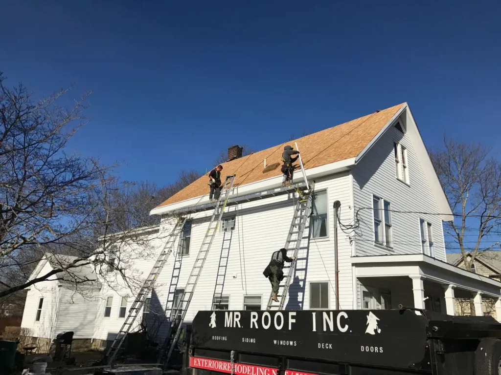 Team of roofing contractors using safety equipment while replacing roof