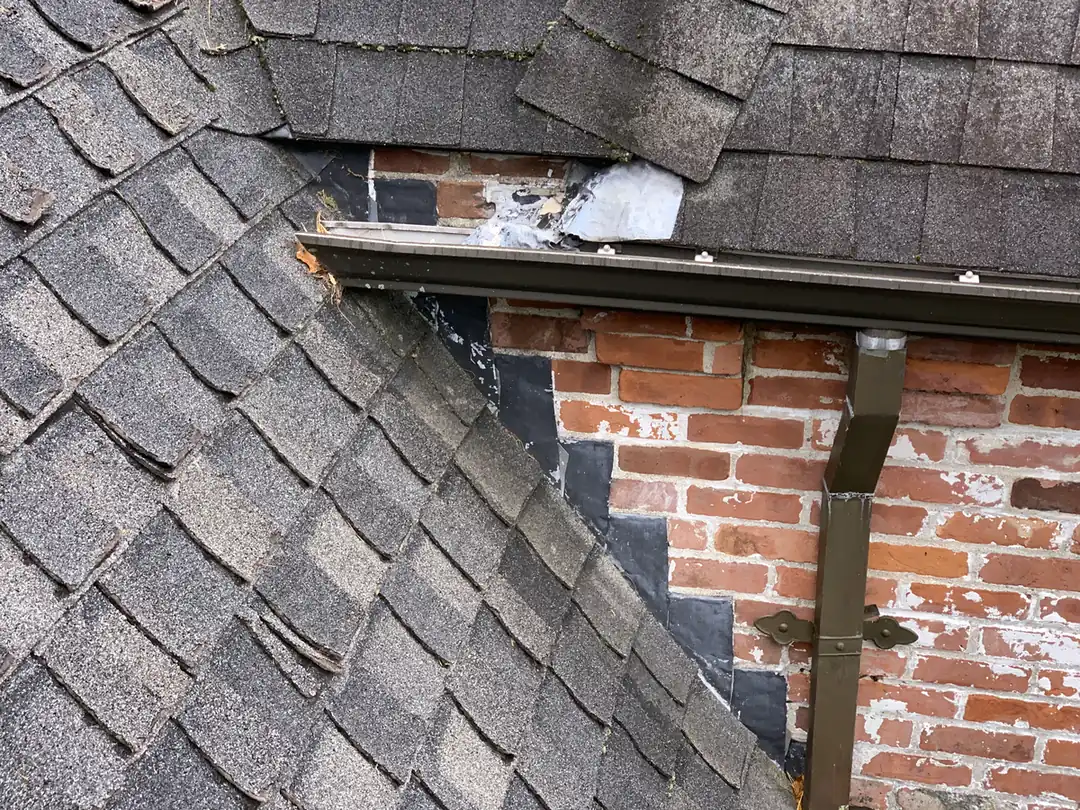 Damaged chimney flashing and surrounding shingles before repair
